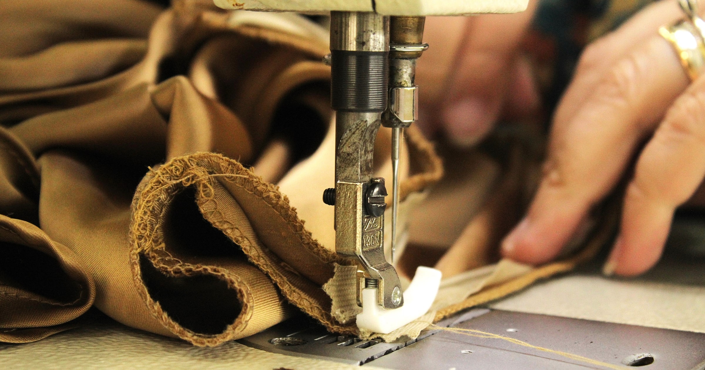 Close-up of hands guiding fabric under a sewing machine needle
