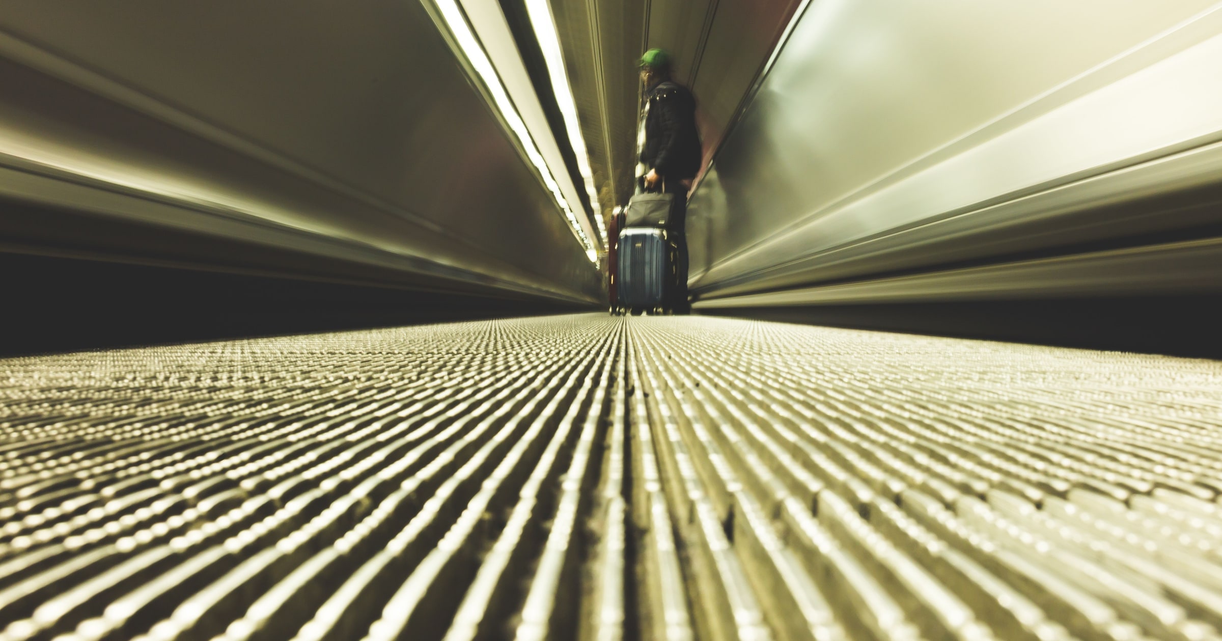 A traveler with a suitcase on a moving walkway