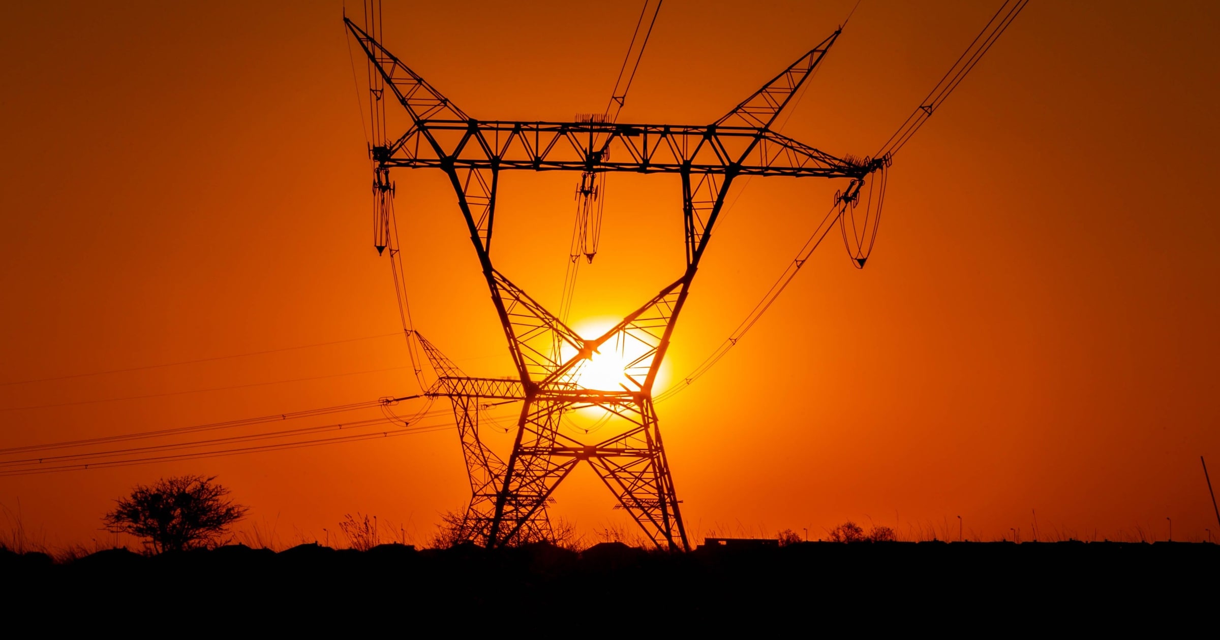 Power lines silhouetted against an orange and pink sunset sky.