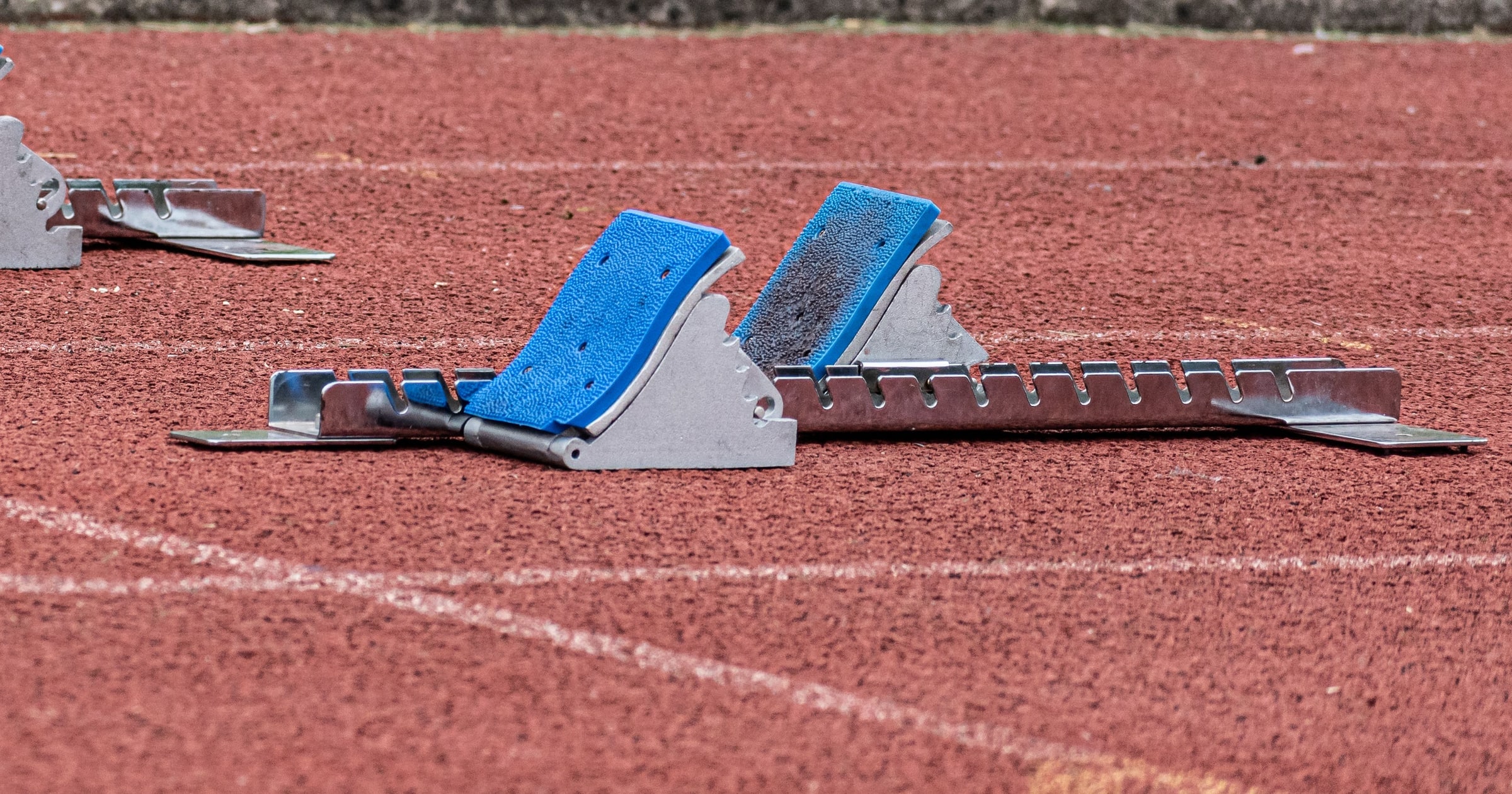 Empty blue starting blocks on a red running track
